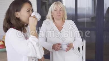 年轻的女人和她的母亲<strong>喝茶</strong>或咖啡，<strong>聊天</strong>。 两个女人分享她们的秘密和问题。 友好
